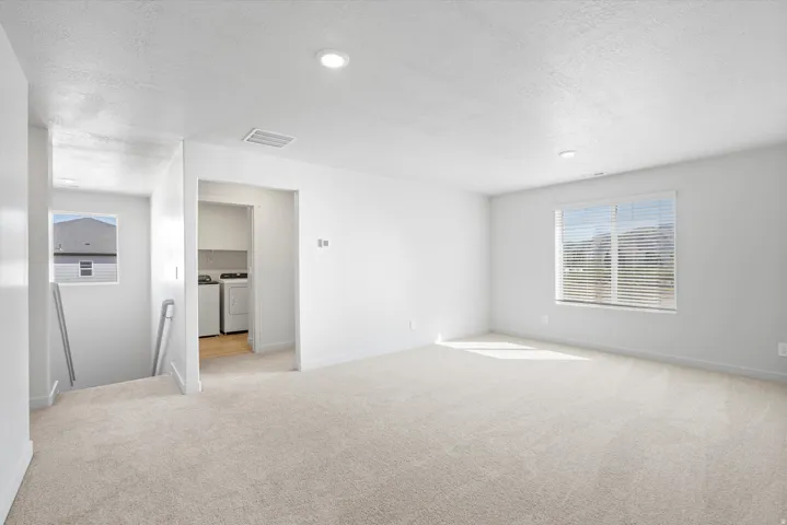 Spacious upper-level room with neutral carpeting and recessed lighting