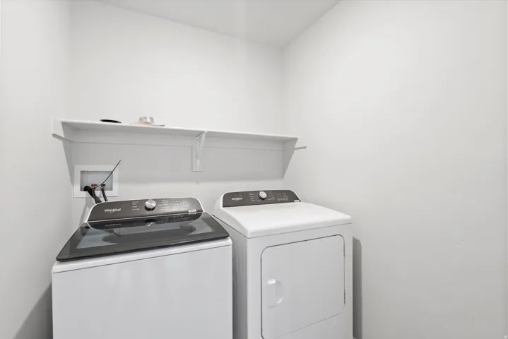 Dedicated laundry area featuring a white wall shelf, utility hookups, and ample vertical space