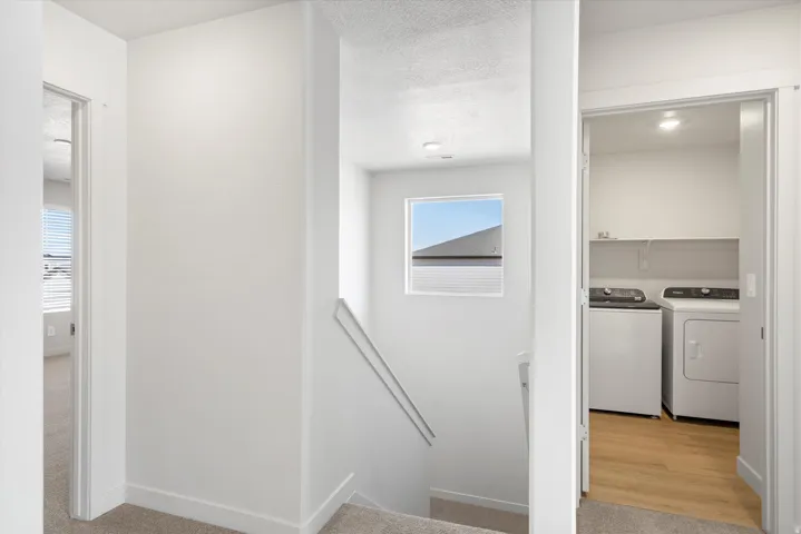 Dedicated laundry area featuring a washer and dryer, wood-finish flooring, and built-in shelving