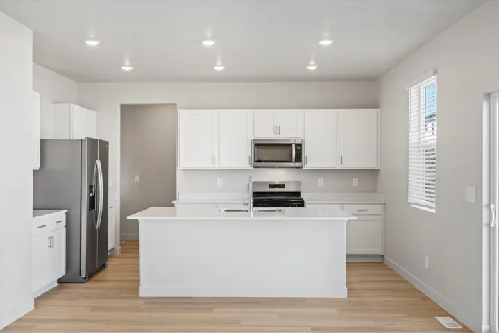 Kitchen featuring white cabinetry, a center island, stainless steel appliances, wood-finish flooring, and recessed lighting