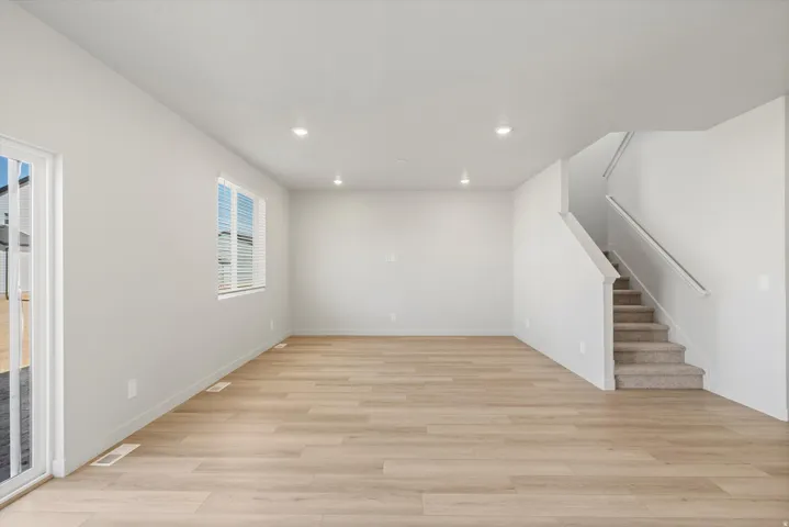 Open-concept living space with light wood-finish flooring, recessed lighting, and a neutral color palette