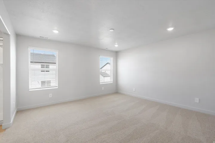 Spacious interior room featuring light-toned carpeting and neutral wall finishes