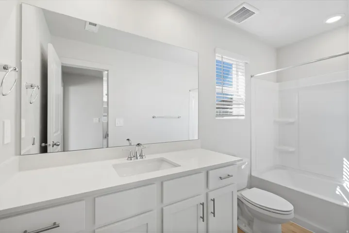 Bathroom featuring a white vanity with an integrated sink, polished chrome faucet, and quartz-finish countertop