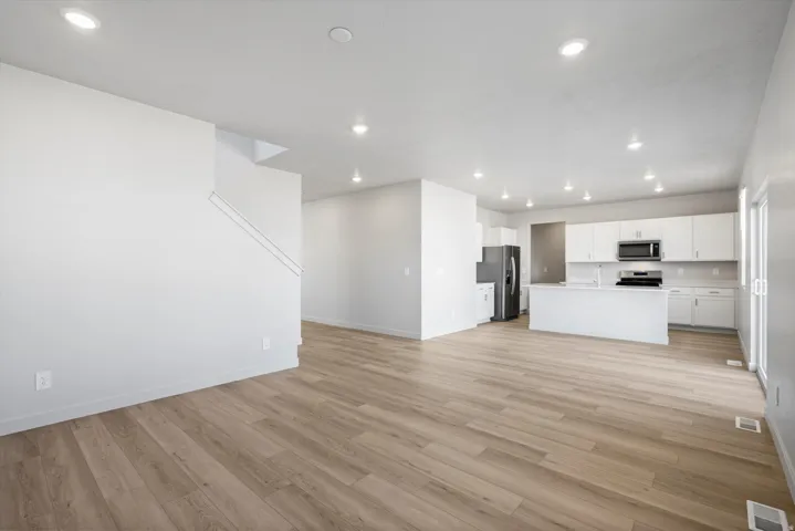 Open-concept living area featuring wood-finish flooring, recessed lighting, and a white color palette