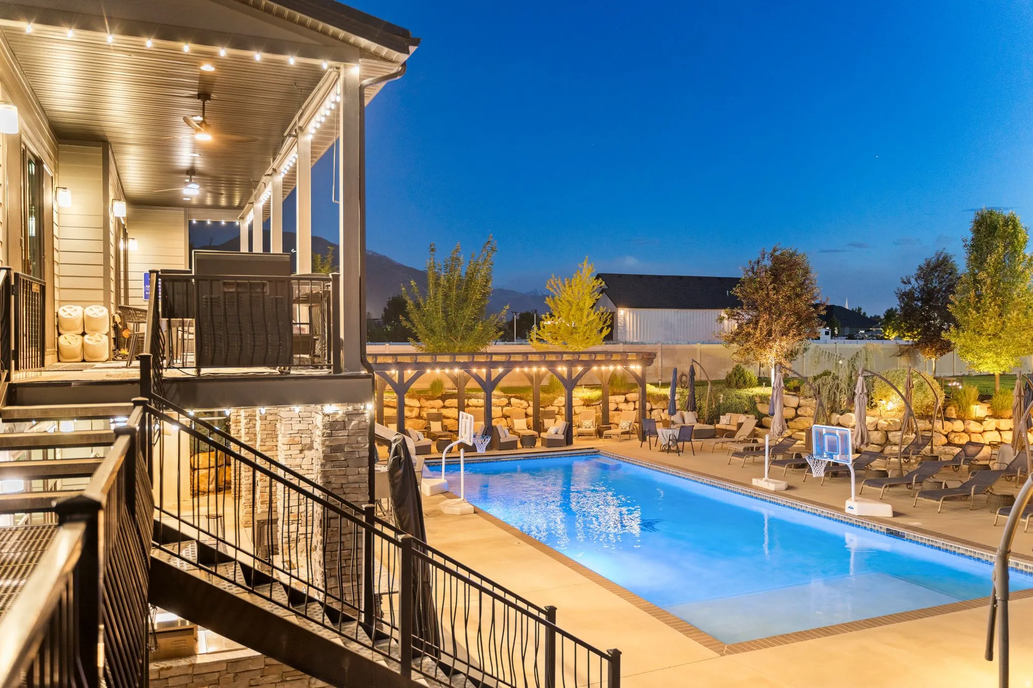 Expansive outdoor living area featuring a rectangular swimming pool with surrounding hardscaping, a wood pergola, and an upper-level covered patio