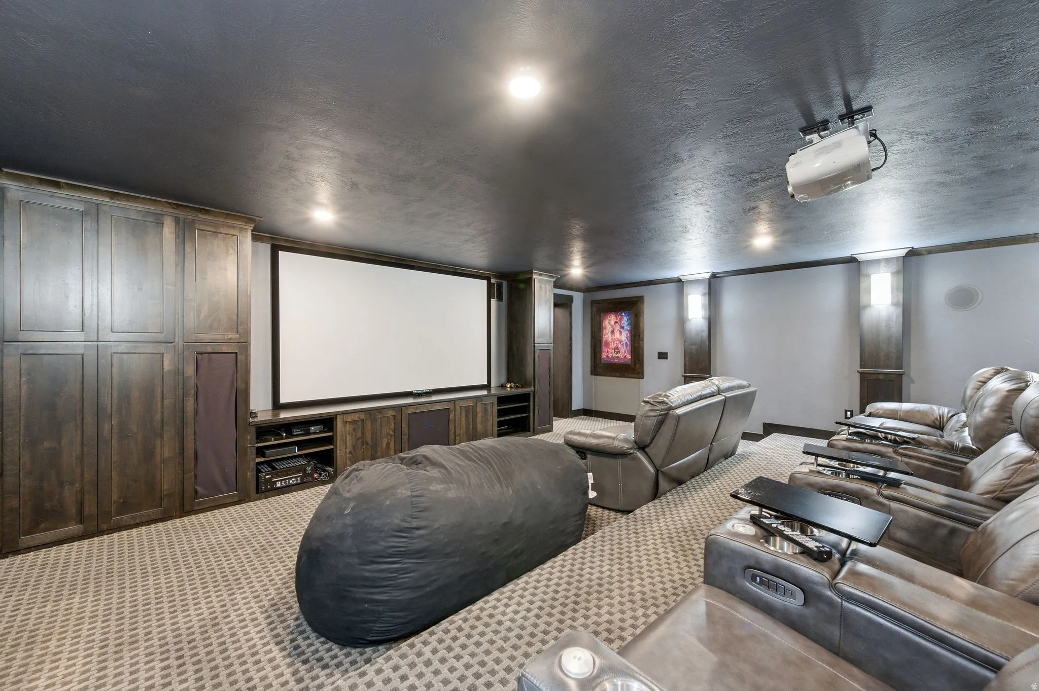 Dedicated media room featuring a large projection screen and built-in entertainment cabinetry
