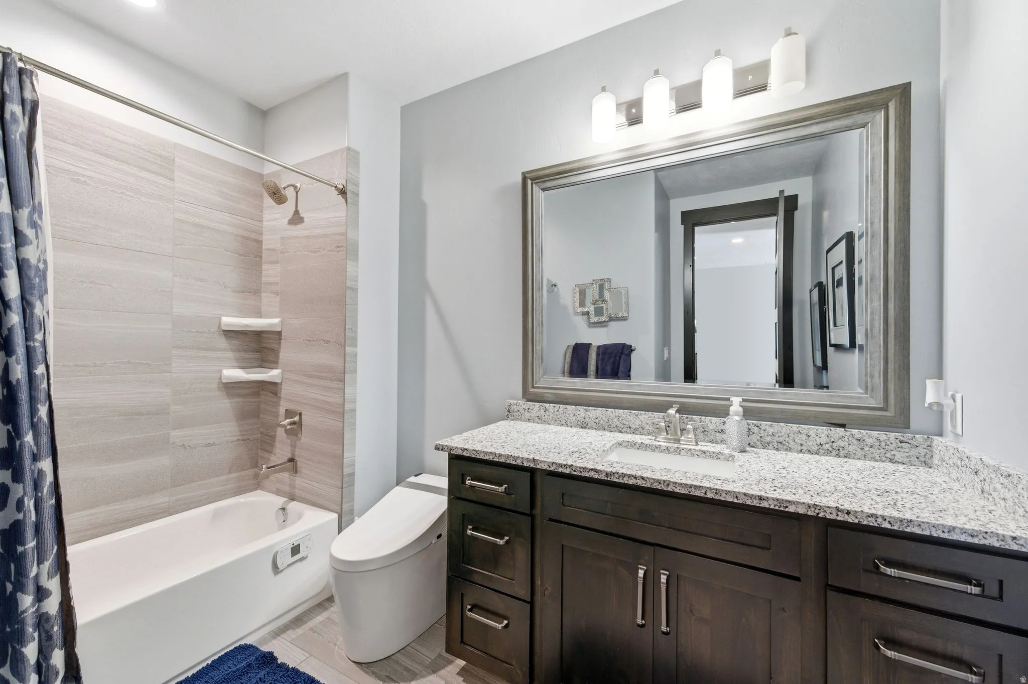 Bathroom featuring a single vanity with granite countertop, undermount sink, and dark wood cabinetry