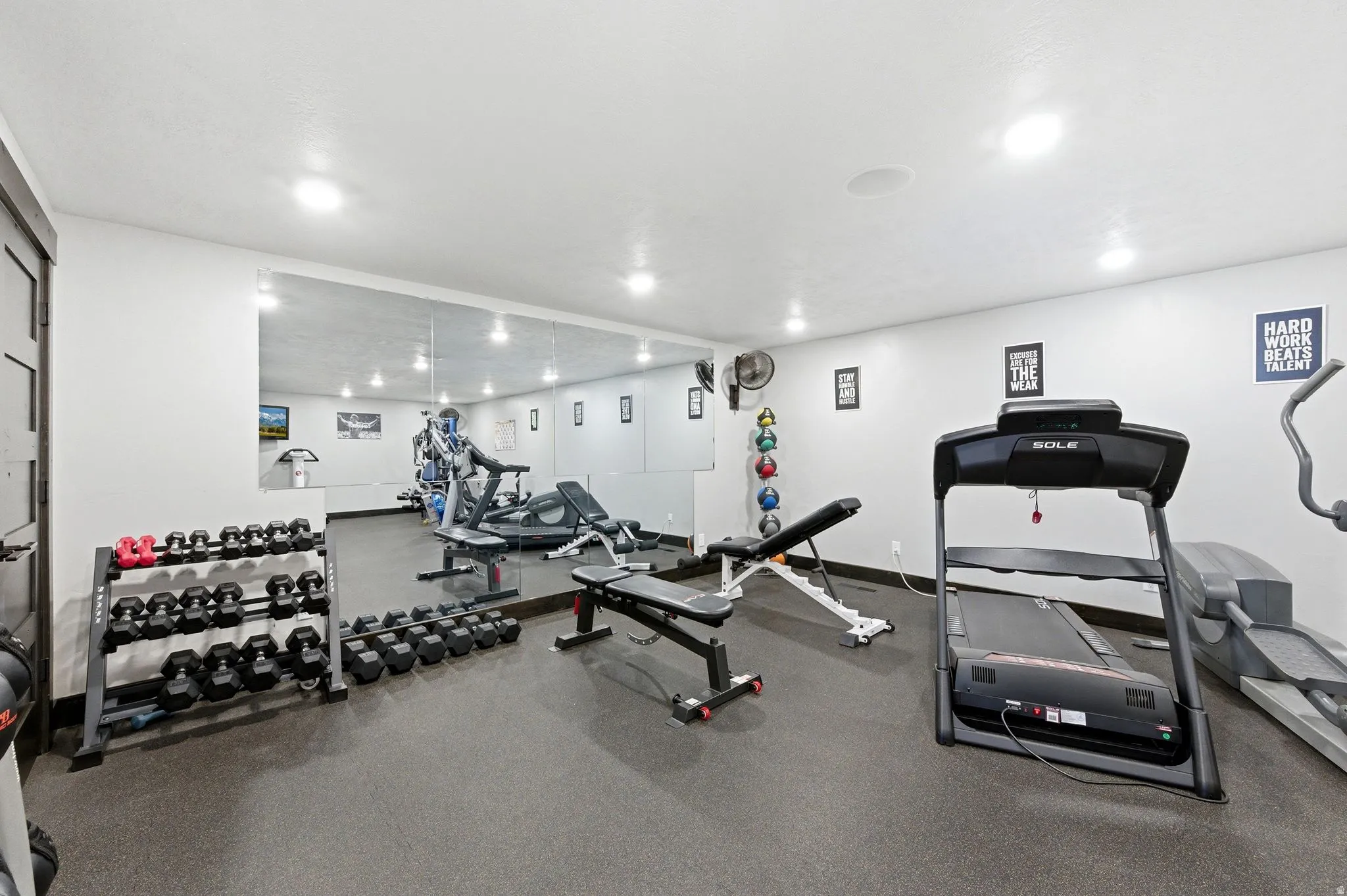 Dedicated exercise space featuring rubber flooring, recessed lighting, and a full-wall mirror