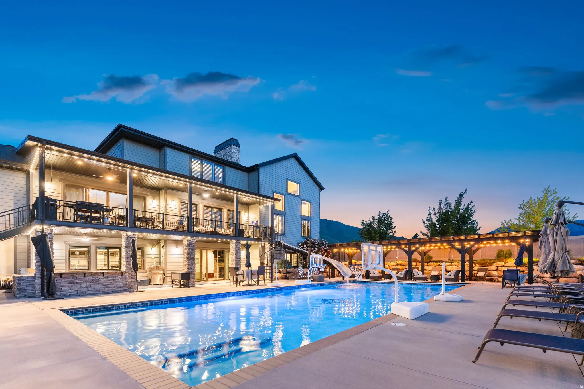 Expansive inground pool with integrated slide and surrounding concrete patio