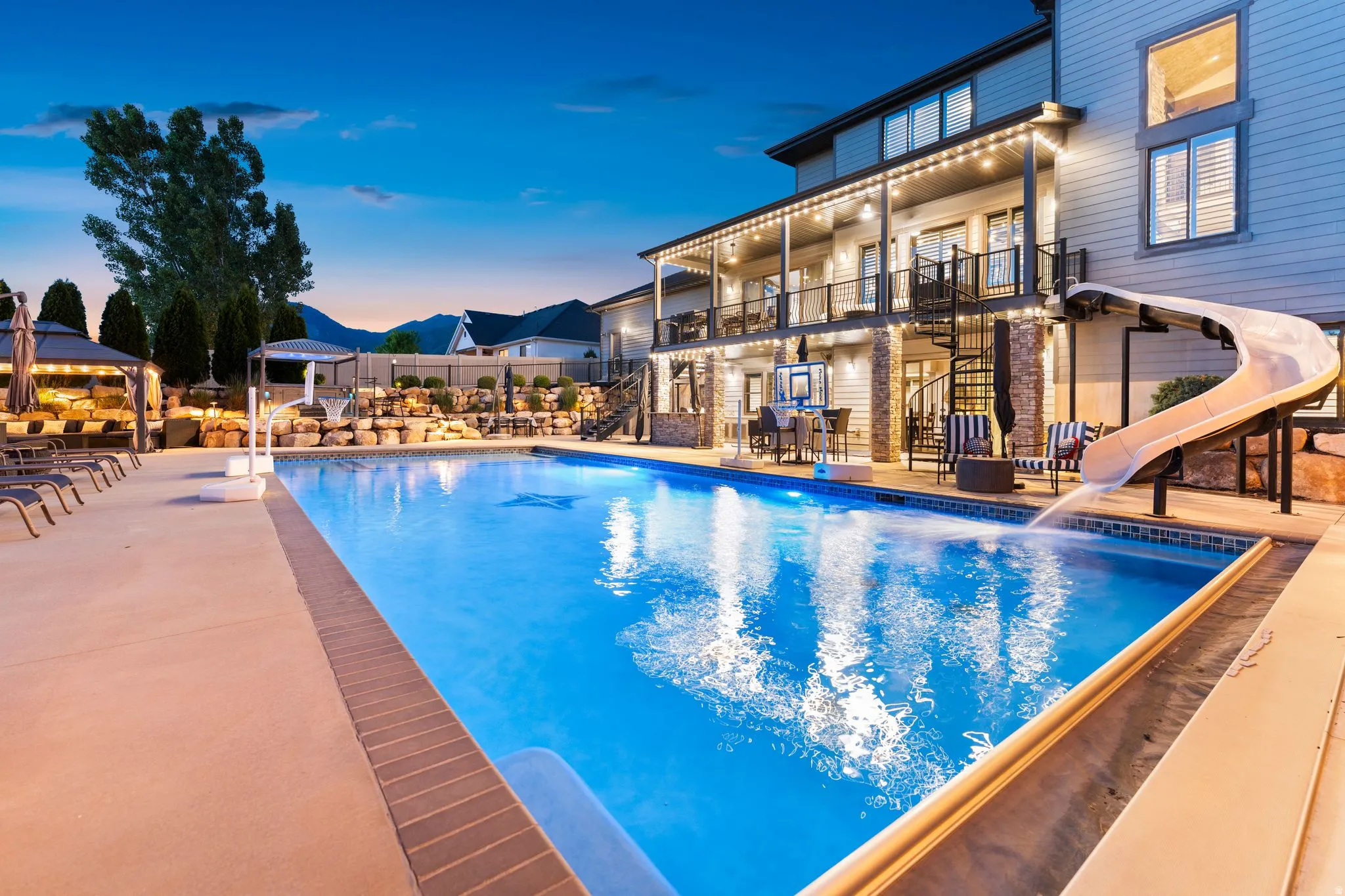 Expansive outdoor living area featuring a large swimming pool with an integrated slide