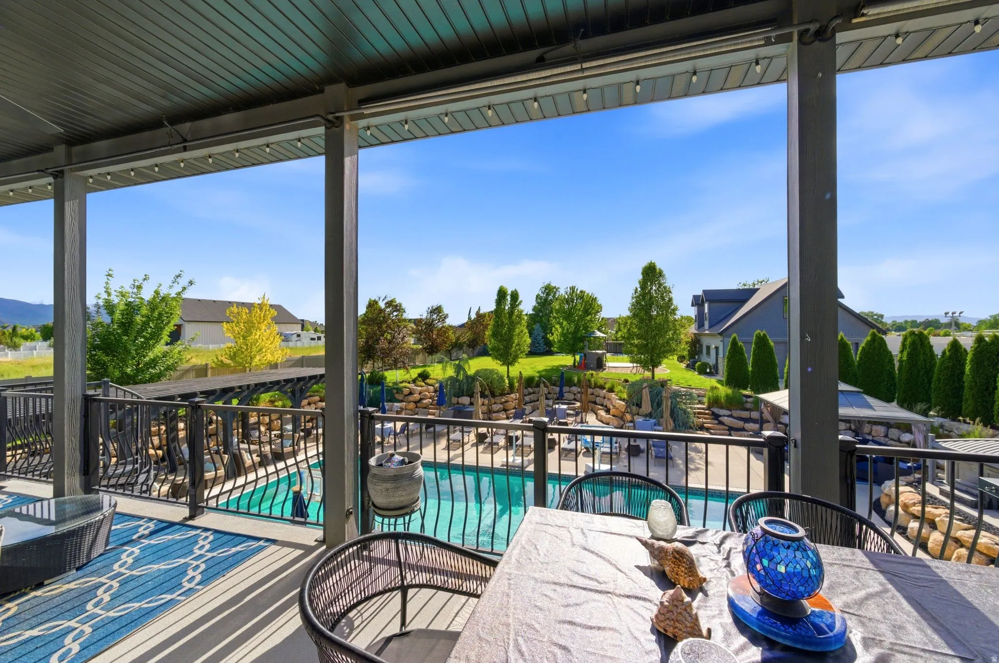 Covered outdoor living space featuring a tongue-and-groove ceiling with string lights, composite decking, and metal railings