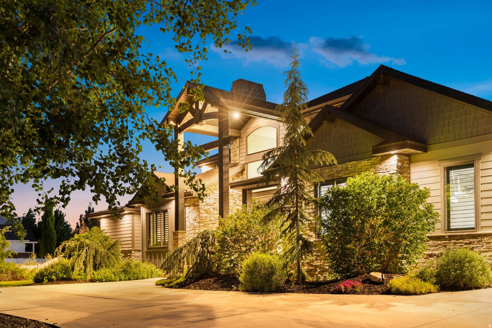 Craftsman-style exterior featuring stone veneer, horizontal siding, exposed timber accents, and prominent gables