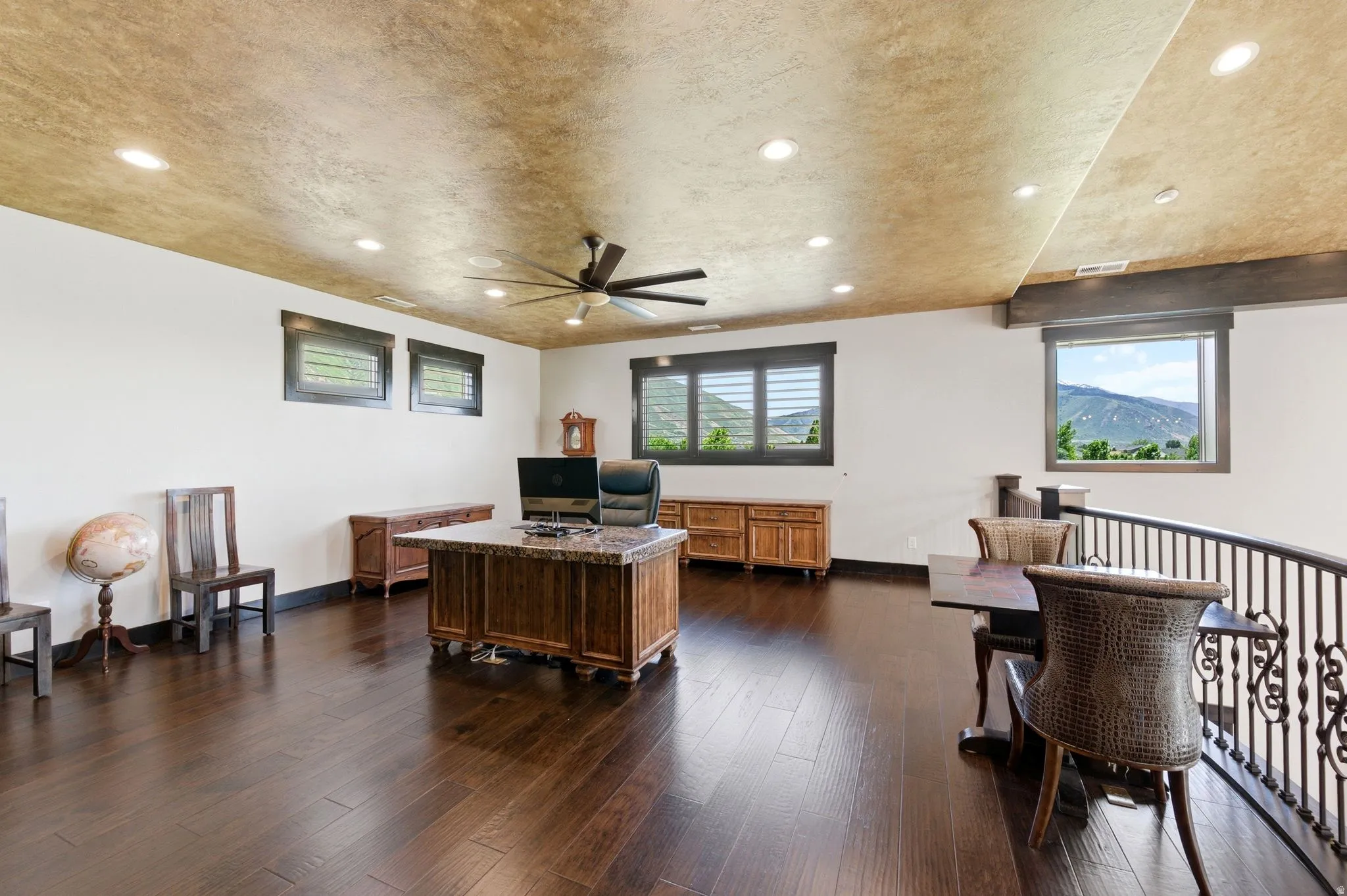 Spacious upper-level room featuring dark wood-finish flooring, a decorative ceiling, and recessed lighting