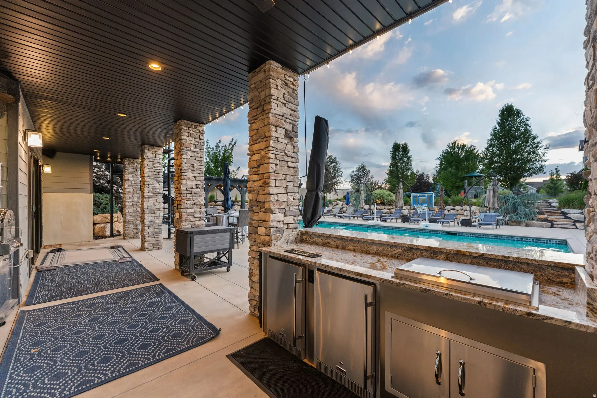 Covered patio featuring an outdoor kitchen with stainless steel appliances and a stone countertop