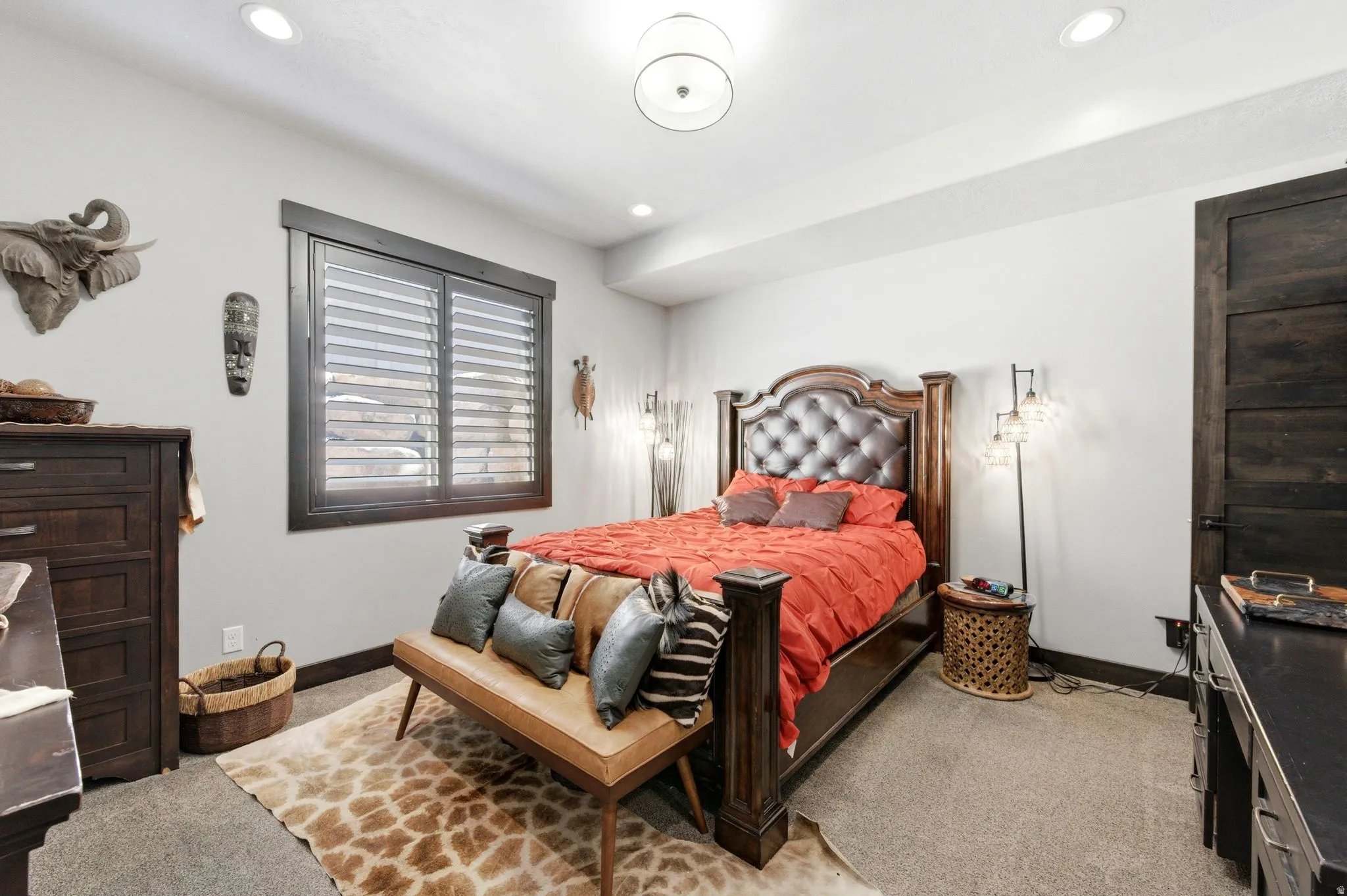 Recessed lighting illuminates the room, featuring a dark wood-finish paneled door and matching window trim with plantation shutters