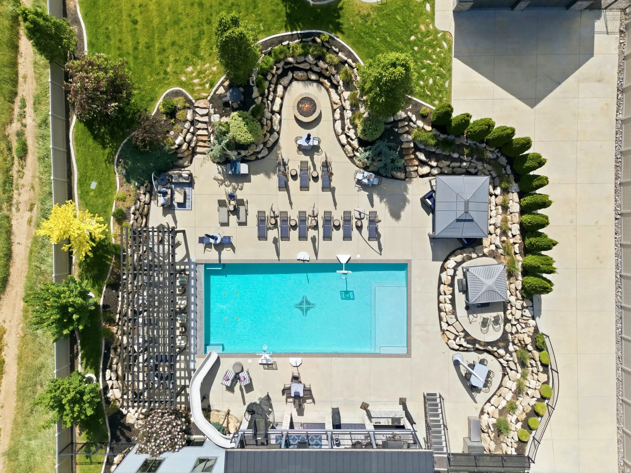Expansive outdoor area featuring a rectangular pool, pergola-covered patio, and extensive hardscaping