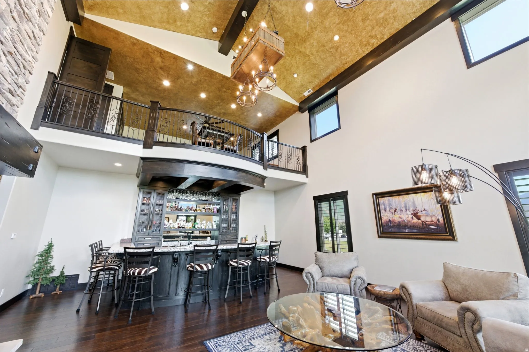 Spacious living area featuring a built-in wet bar with seating, dark wood-finish flooring, and a stone-clad wall accent