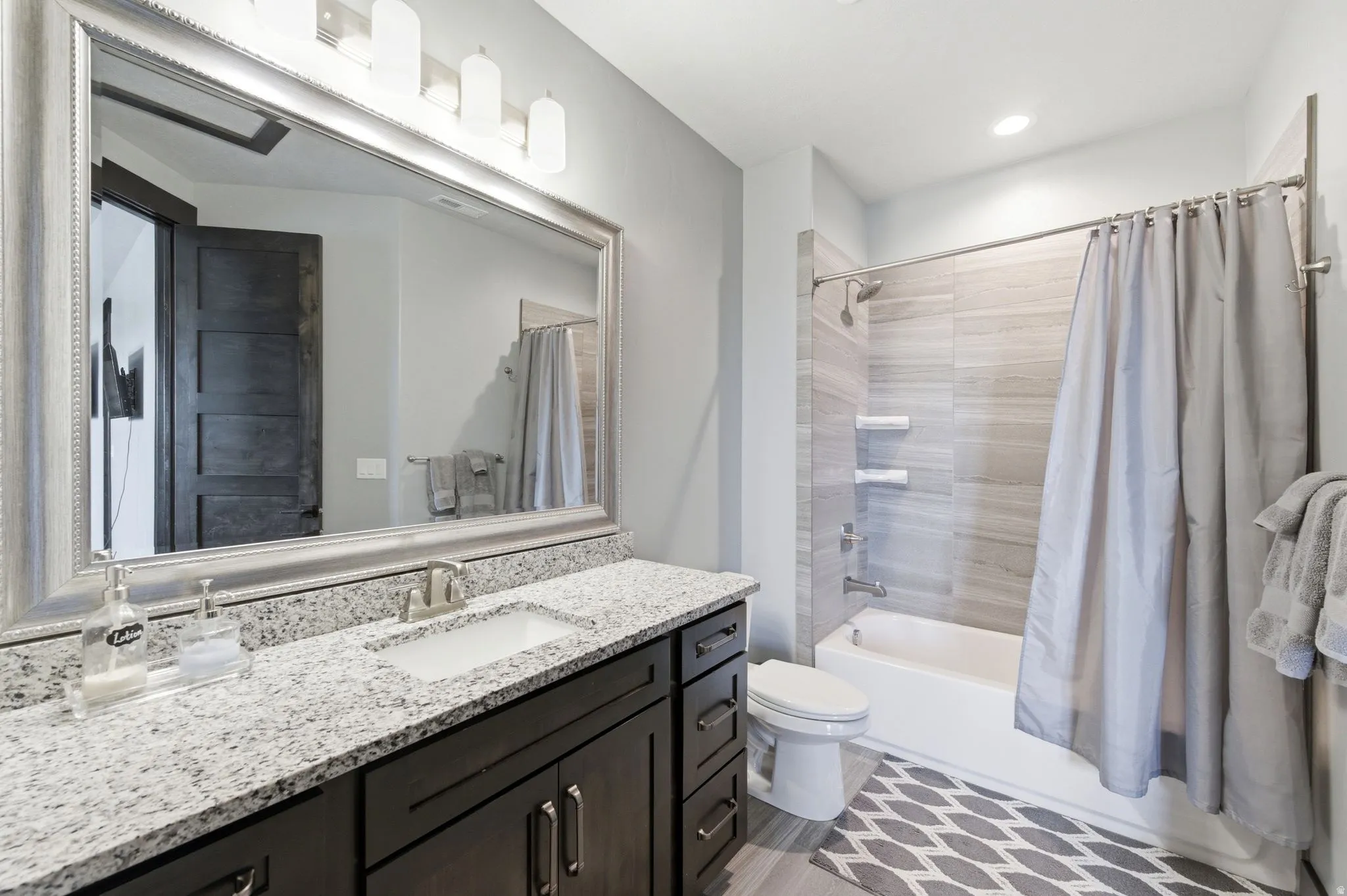Bathroom featuring a dark wood vanity with a white granite countertop, undermount sink, and brushed nickel faucet