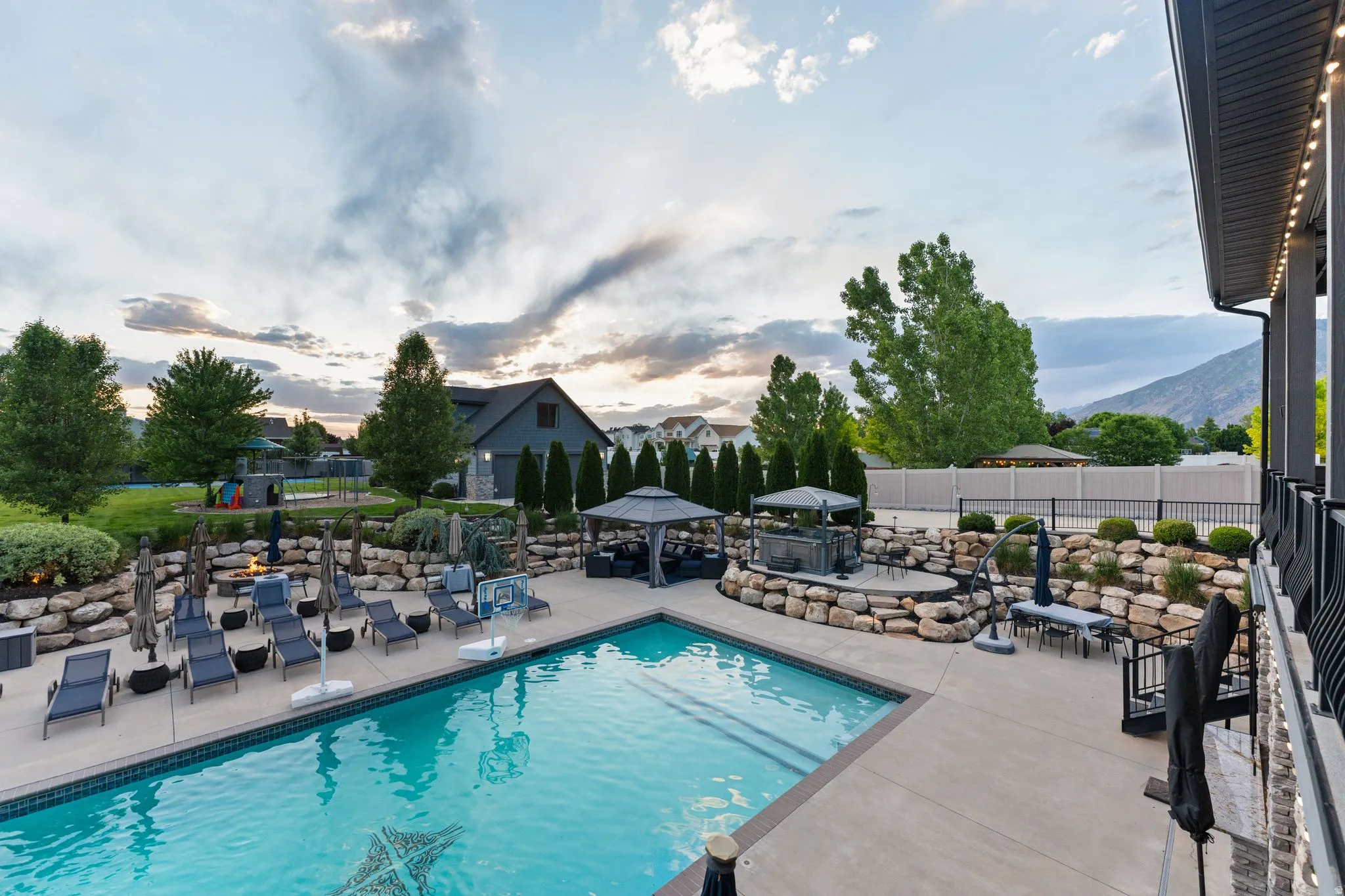 Expansive backyard featuring a rectangular swimming pool with a mosaic detail, a built-in hot tub, and a fire pit area