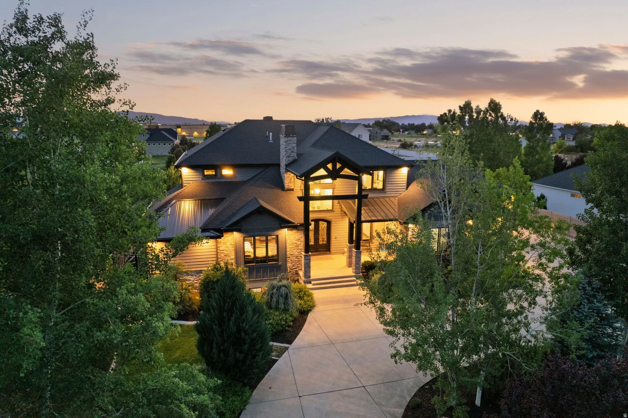 Spacious residence featuring a large driveway, mature landscaping, and a multi-level roofline