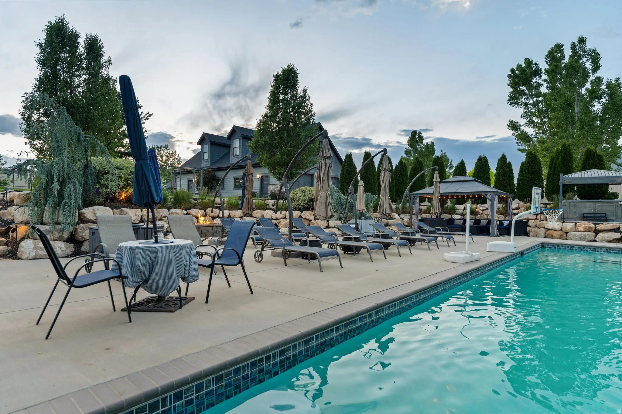 In-ground swimming pool with a tiled edge, surrounded by an expansive concrete patio