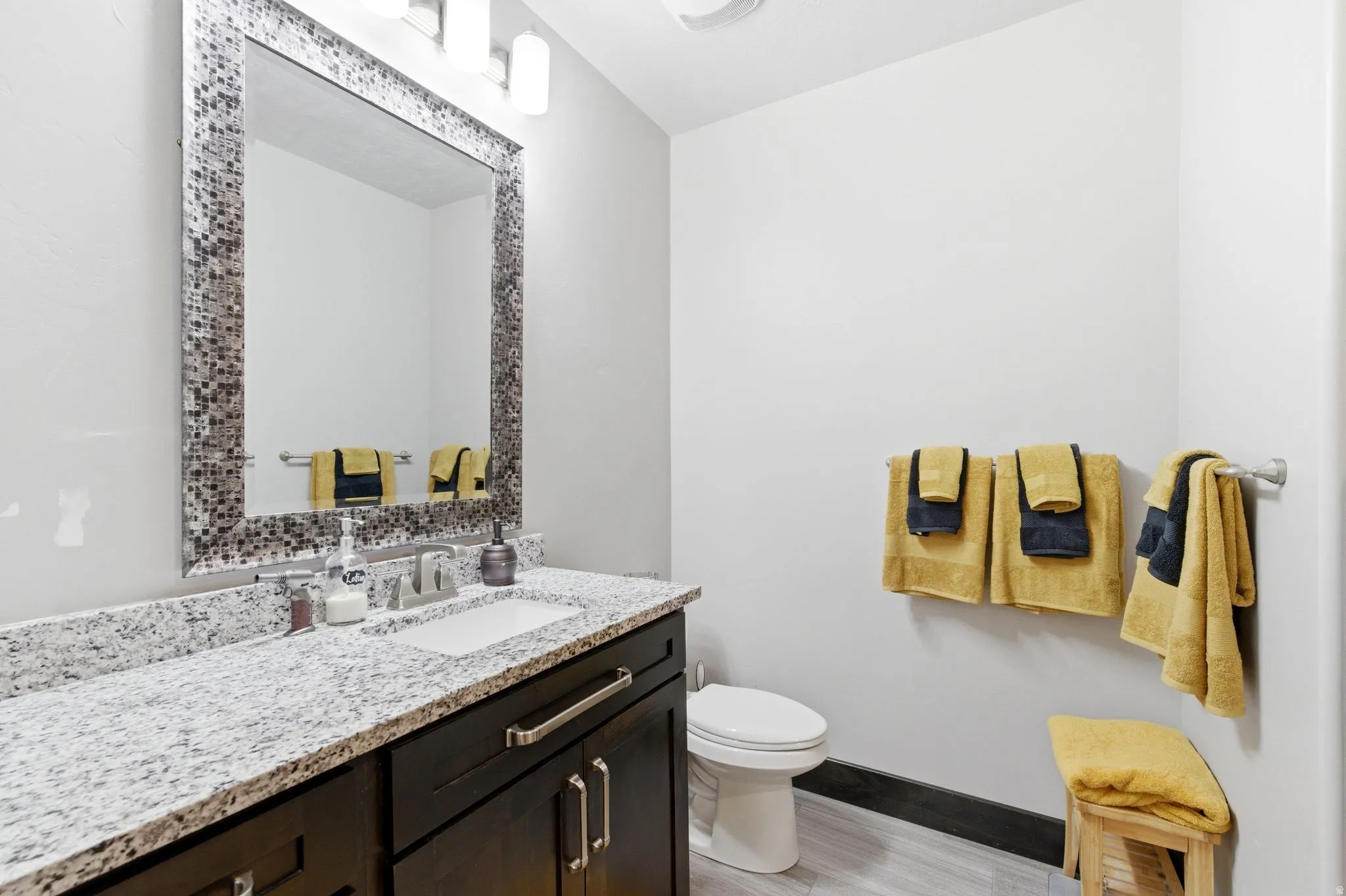 Bathroom vanity featuring a granite countertop, undermount sink, and dark wood cabinetry