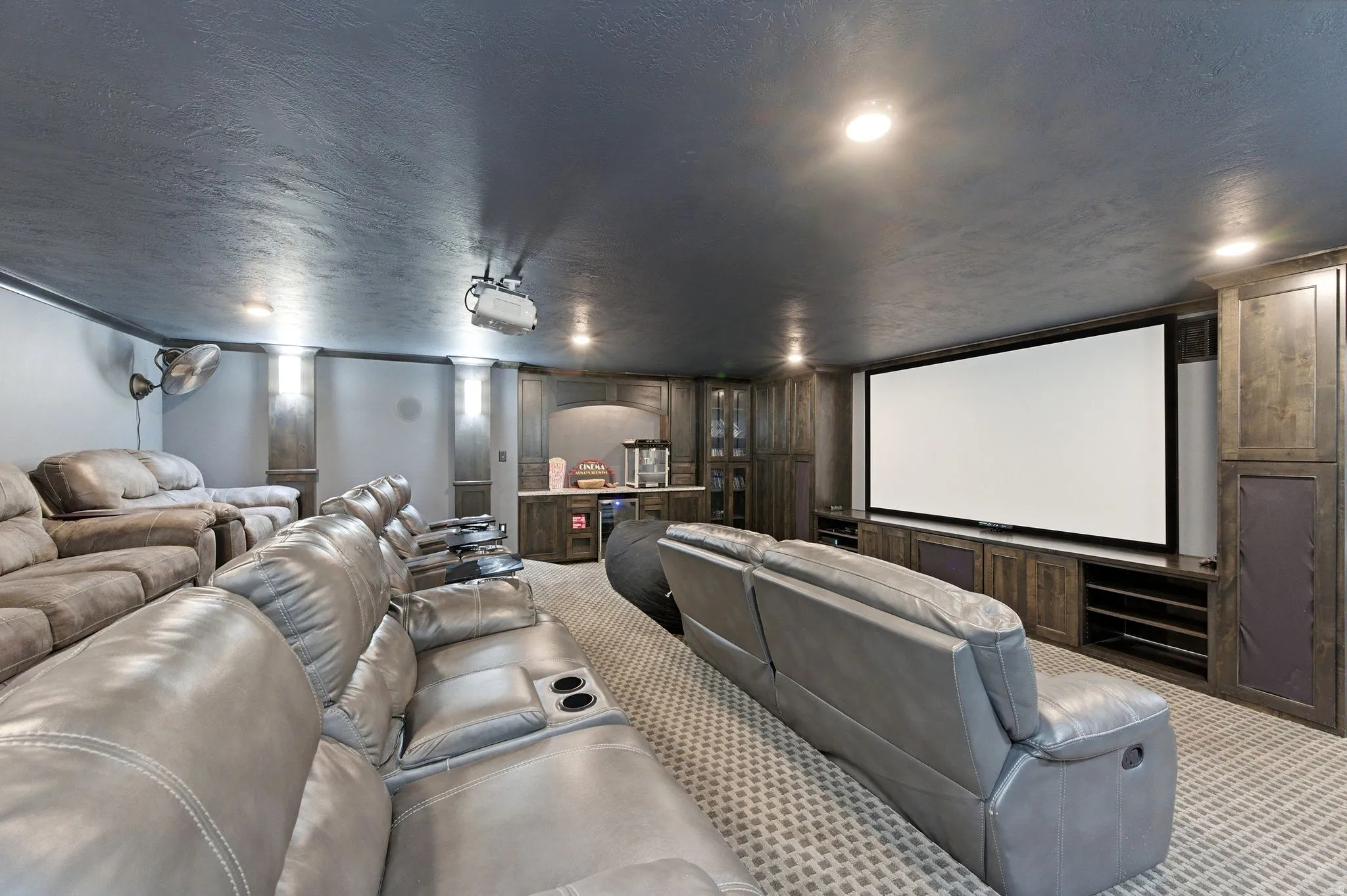 Dedicated home theater featuring a large projection screen, built-in media cabinetry, recessed lighting, a wet bar, and wall-to-wall carpeting