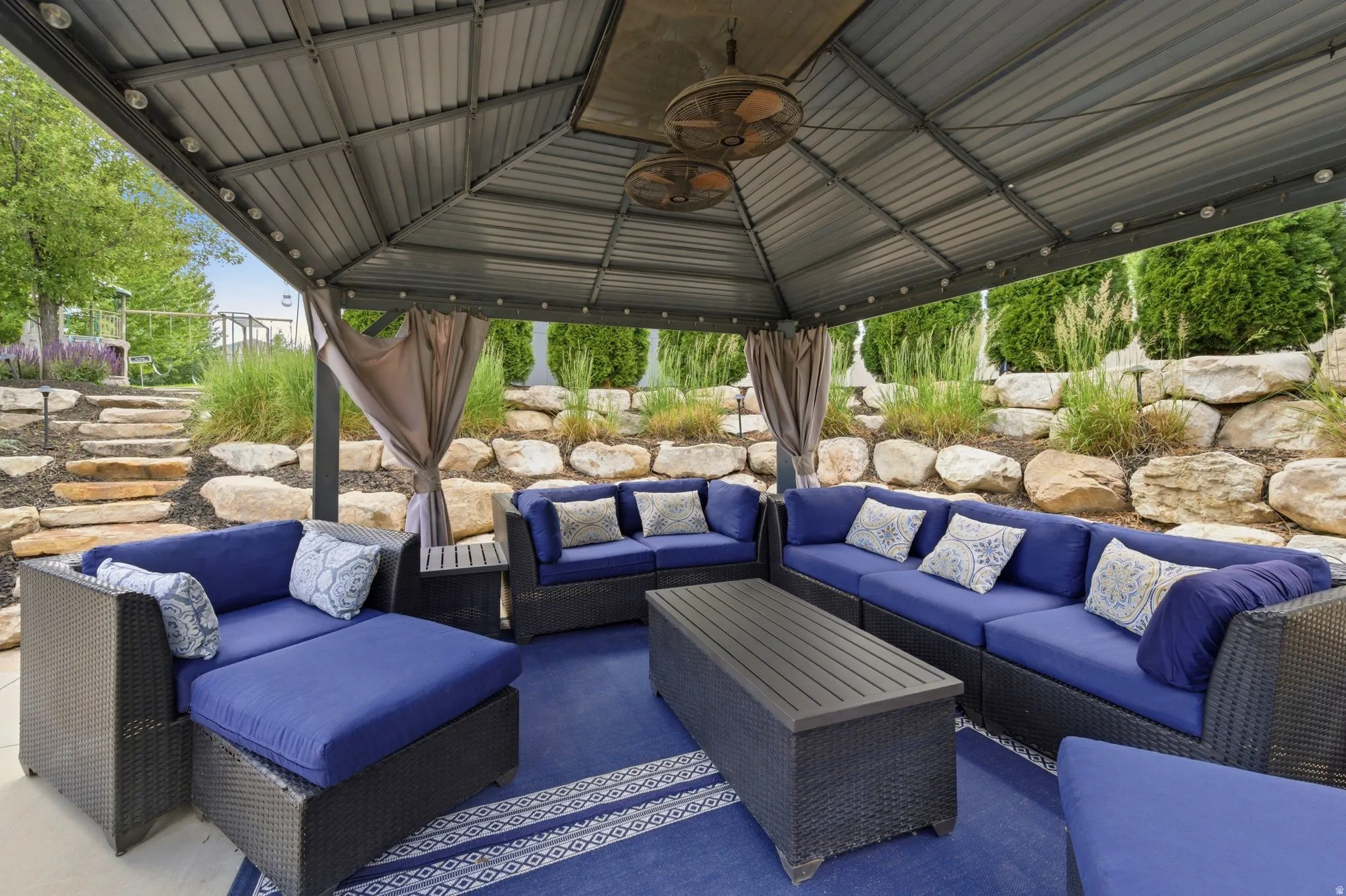 Covered patio featuring a corrugated metal roof, integrated string lighting, and two ceiling fans