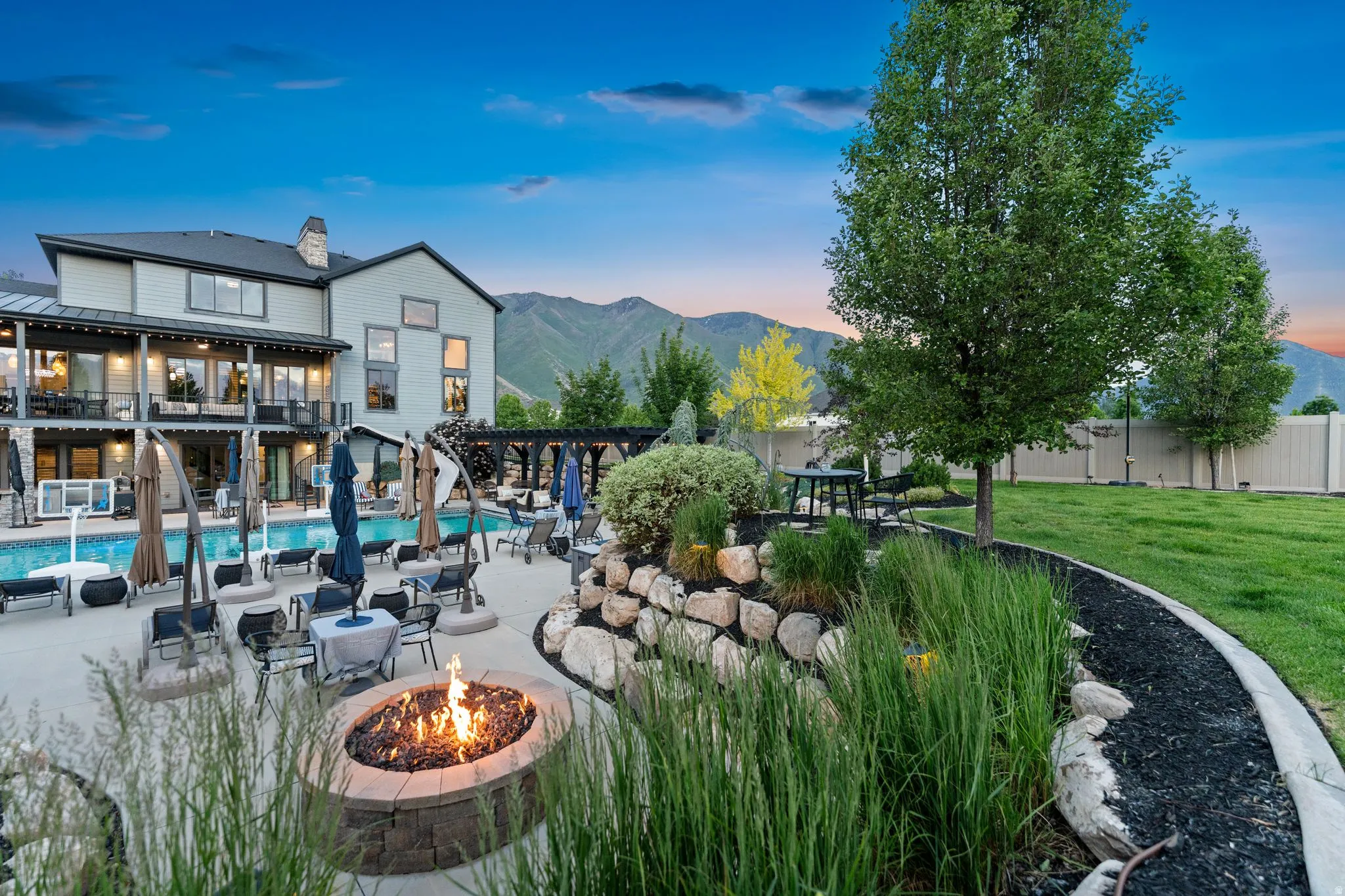 Expansive backyard featuring a custom fire pit, large swimming pool, and a multi-level patio