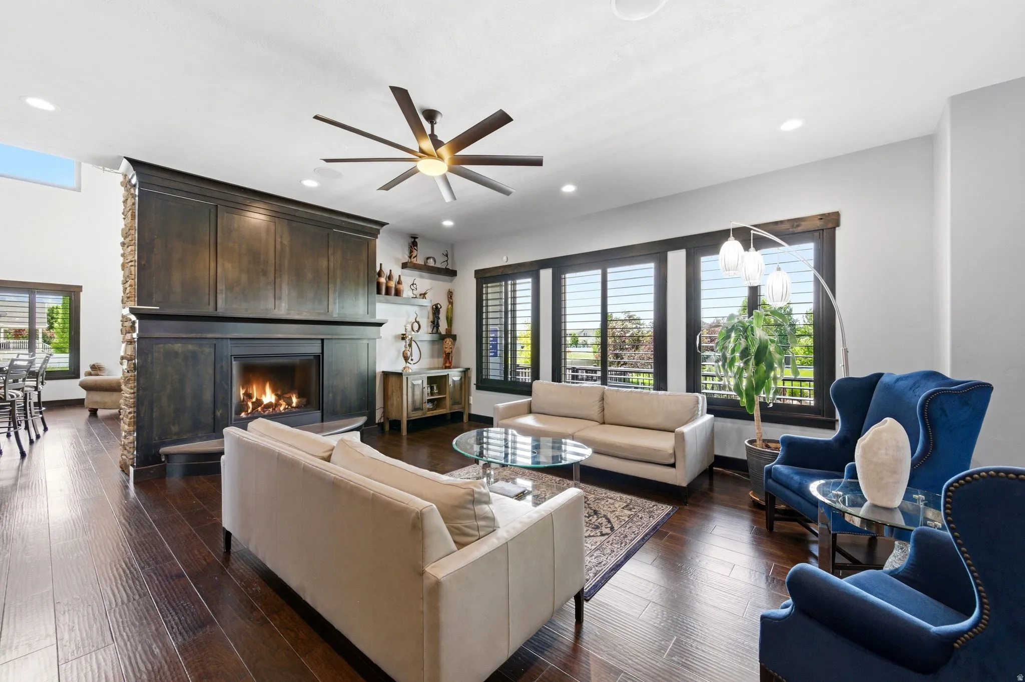 Spacious living area featuring rich wood-finish flooring and a stone-clad fireplace with a dark wood mantel