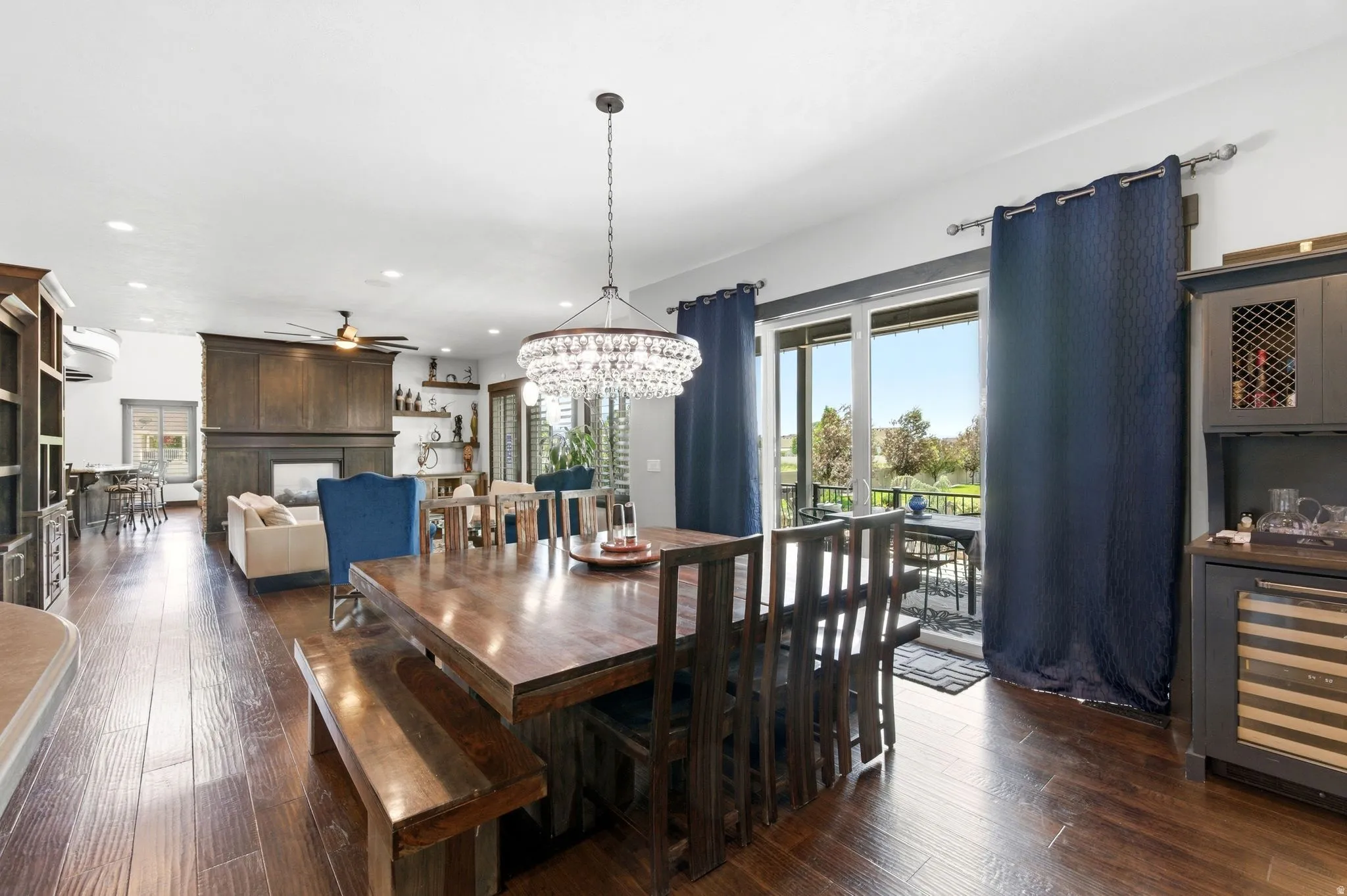 Open-concept dining area featuring wood-finish flooring, a contemporary chandelier, and direct access to an outdoor patio via sliding glass doors