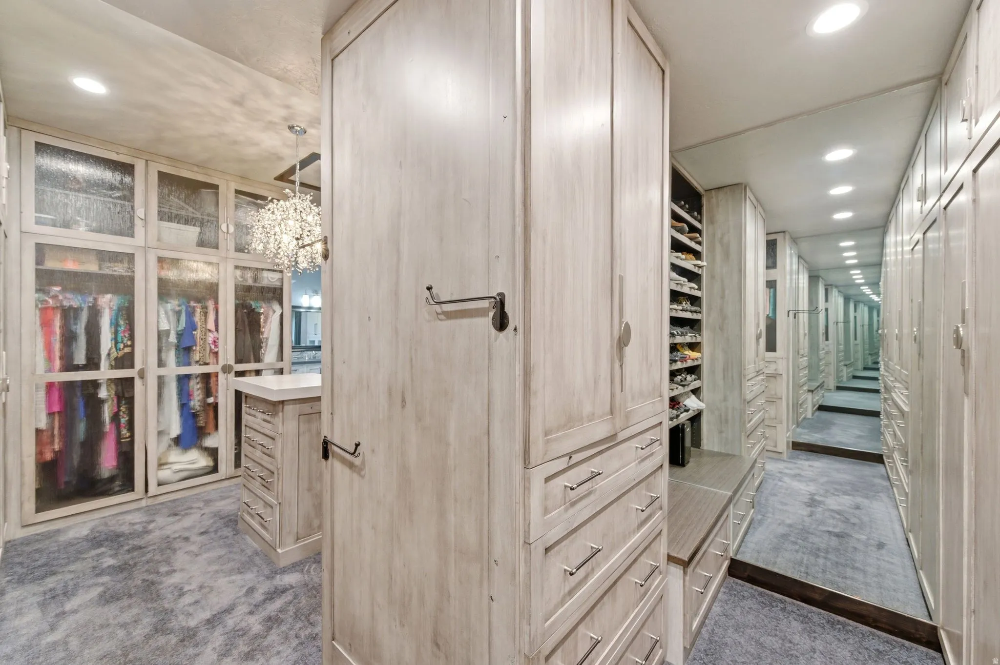 Custom cabinetry in a light wood finish with extensive storage, including glass-fronted wardrobe sections