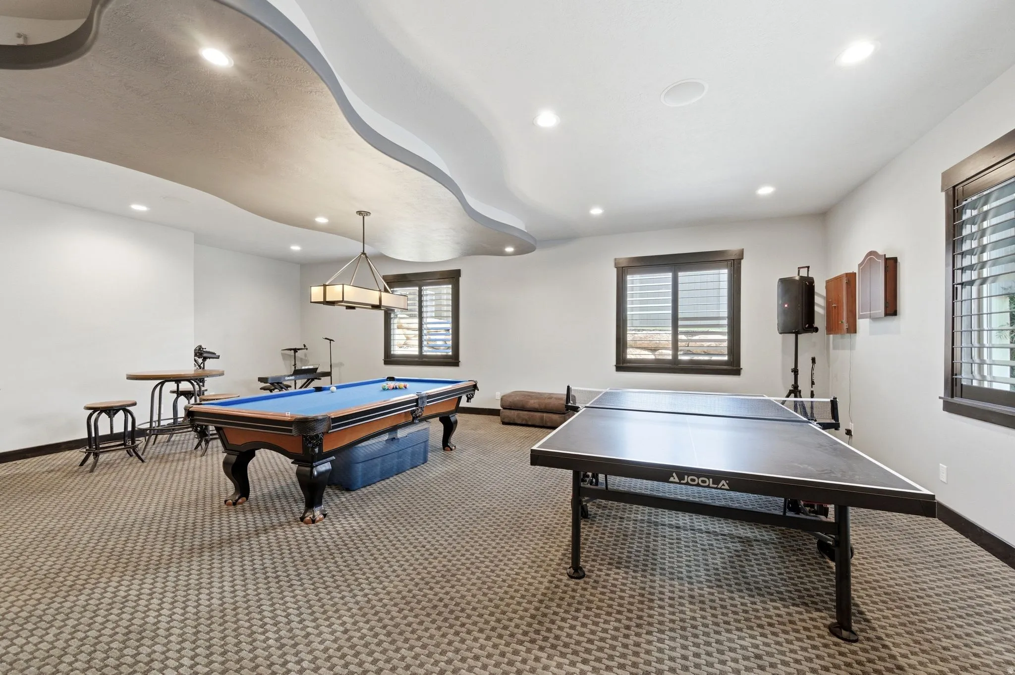 Spacious recreational room featuring a patterned carpet, recessed lighting, and a unique ceiling design