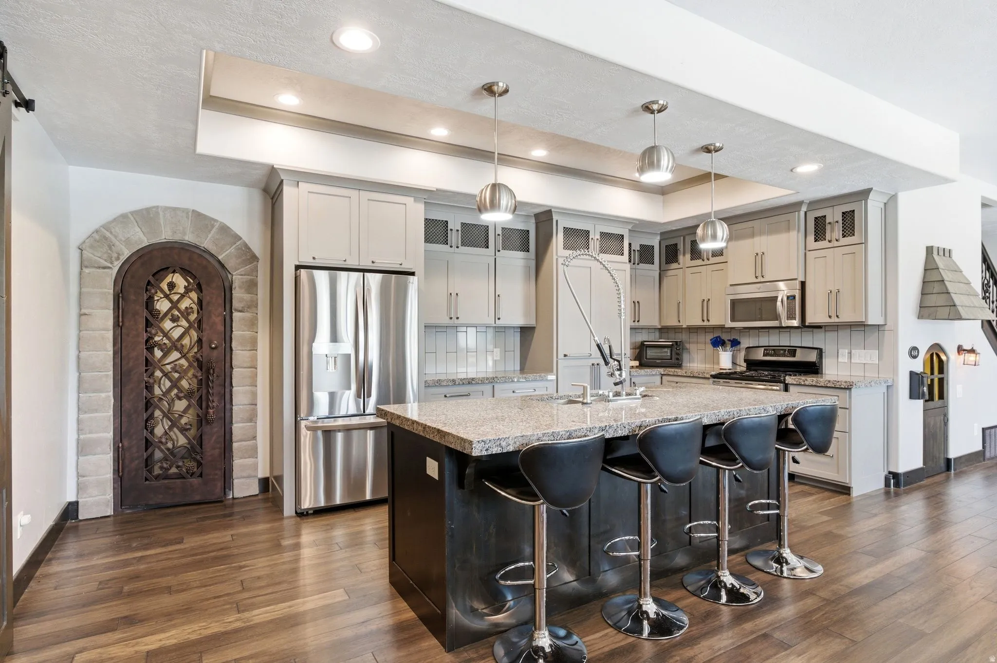 Gourmet kitchen featuring a large island with seating, stainless steel appliances, light-toned cabinetry, and granite countertops