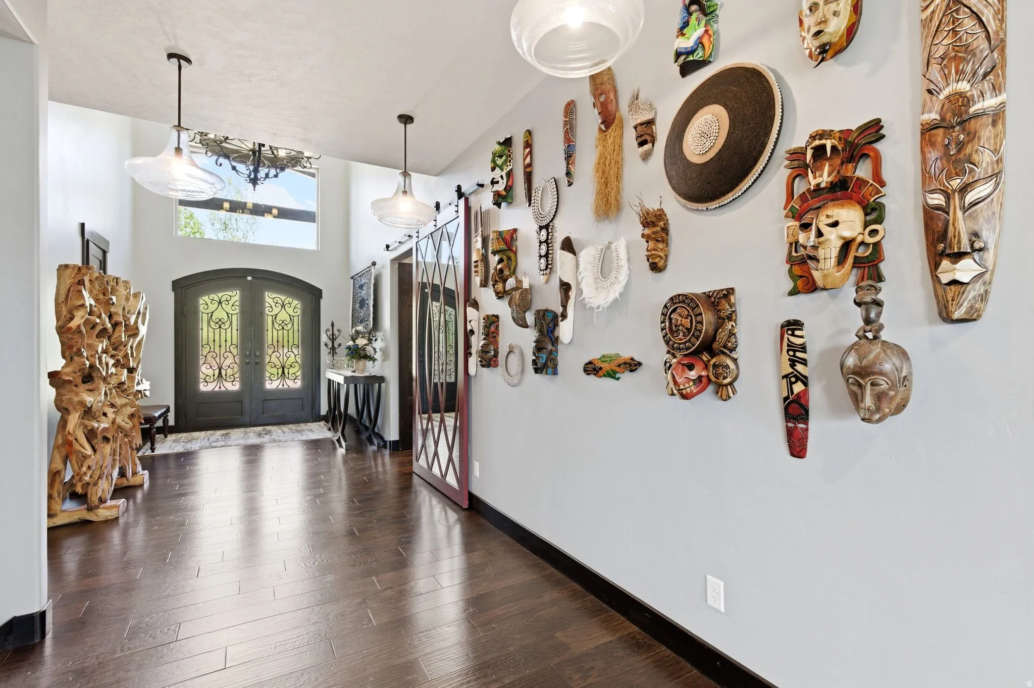 Grand entryway featuring arched double doors with decorative ironwork, a transom window, and dark wood-finish flooring