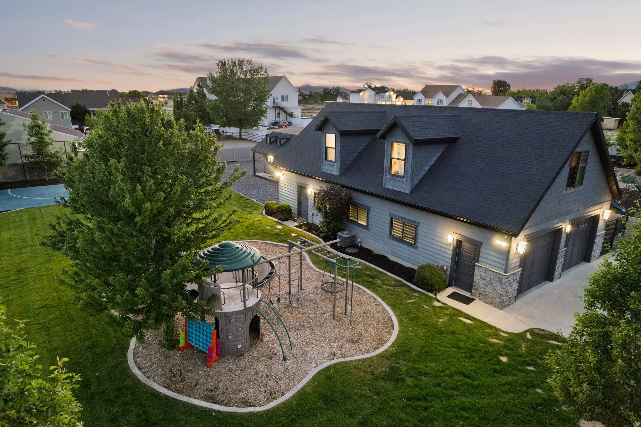 Contemporary detached structure featuring dormer windows, a two-car garage, and stone veneer accents