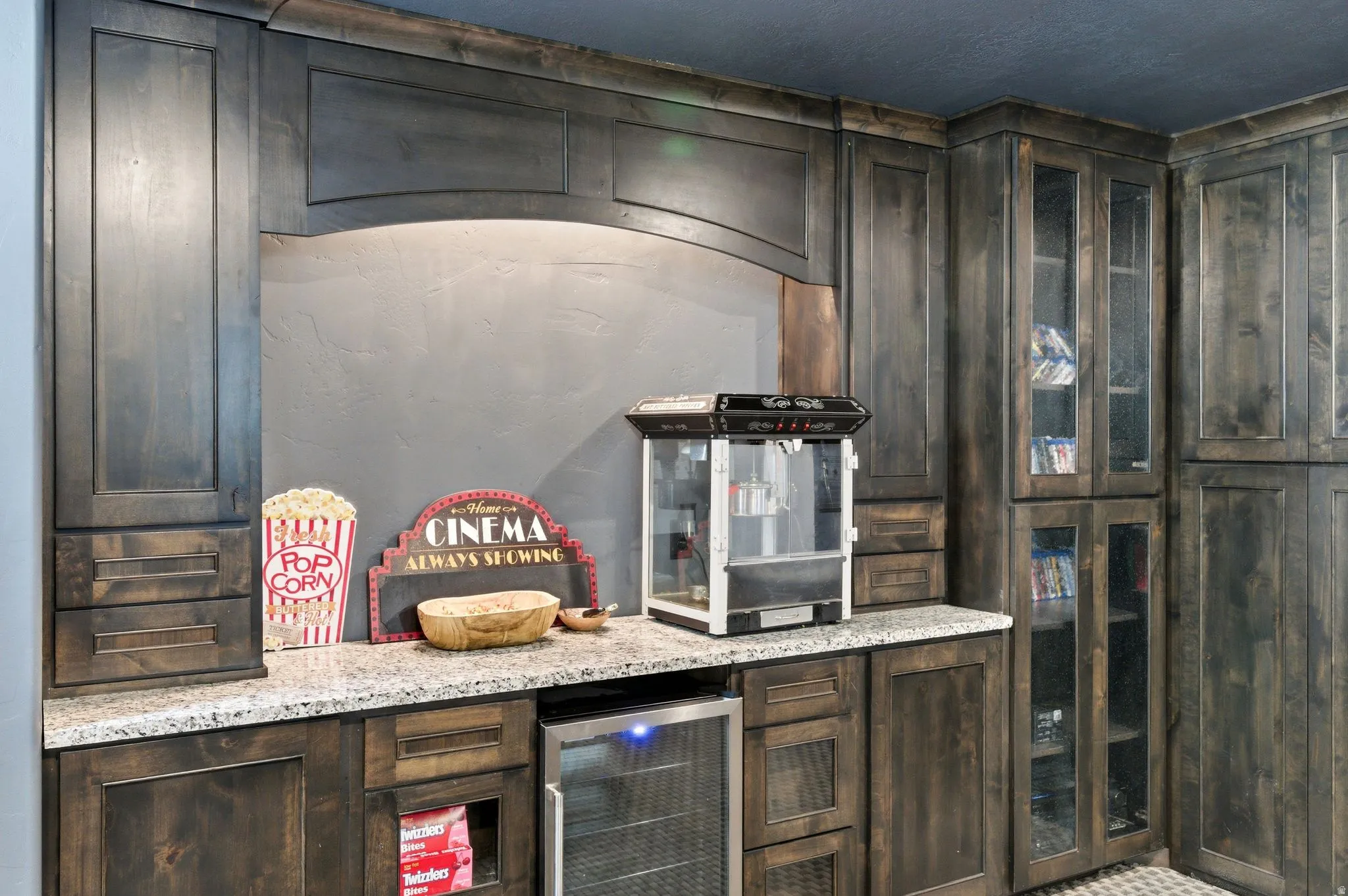 Custom built-in cabinetry with a granite countertop, under-cabinet lighting, and glass-front display cabinets