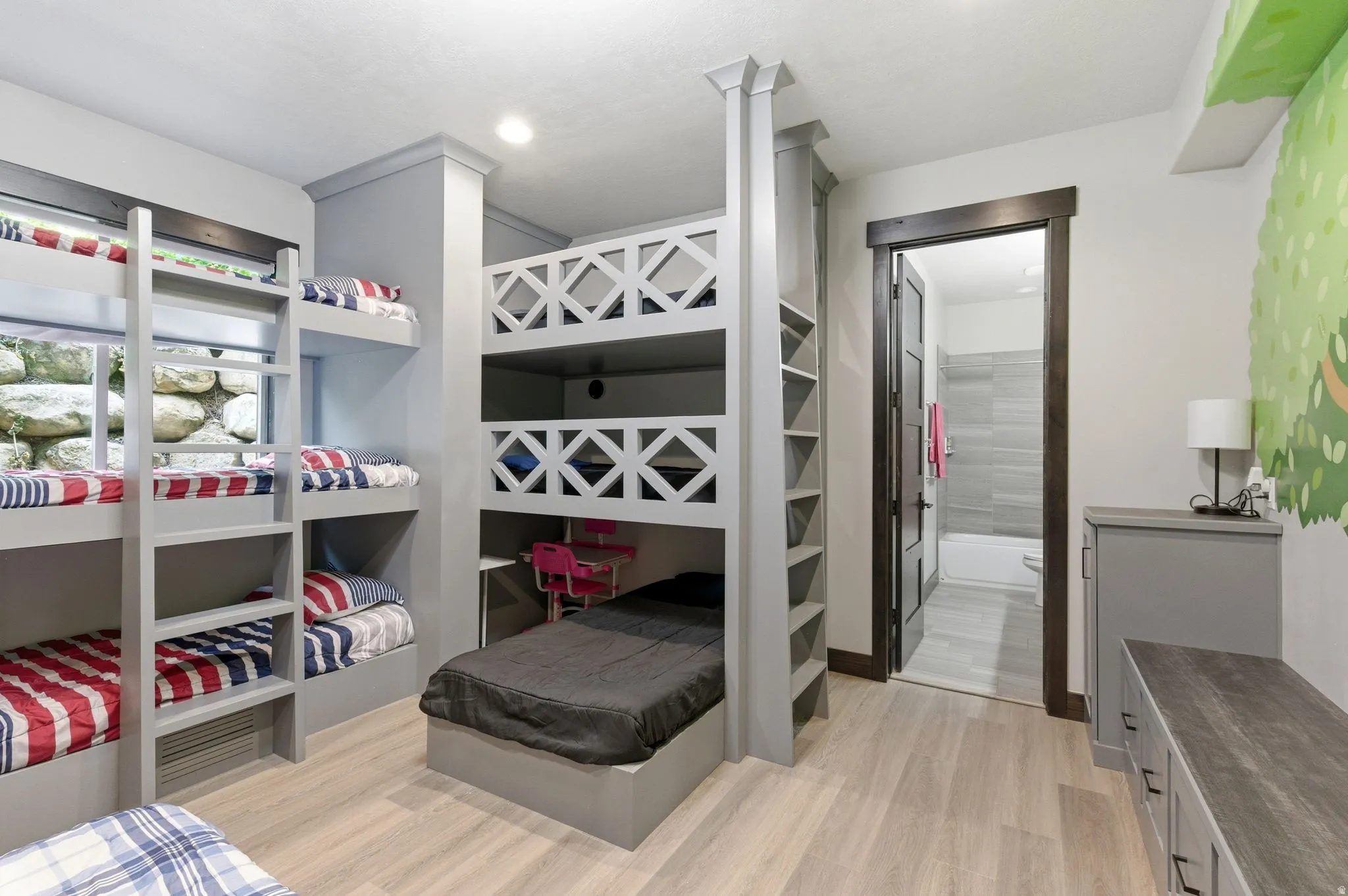 Built-in bunk beds with integrated ladders and shelving, featuring a window with a stone exterior backdrop