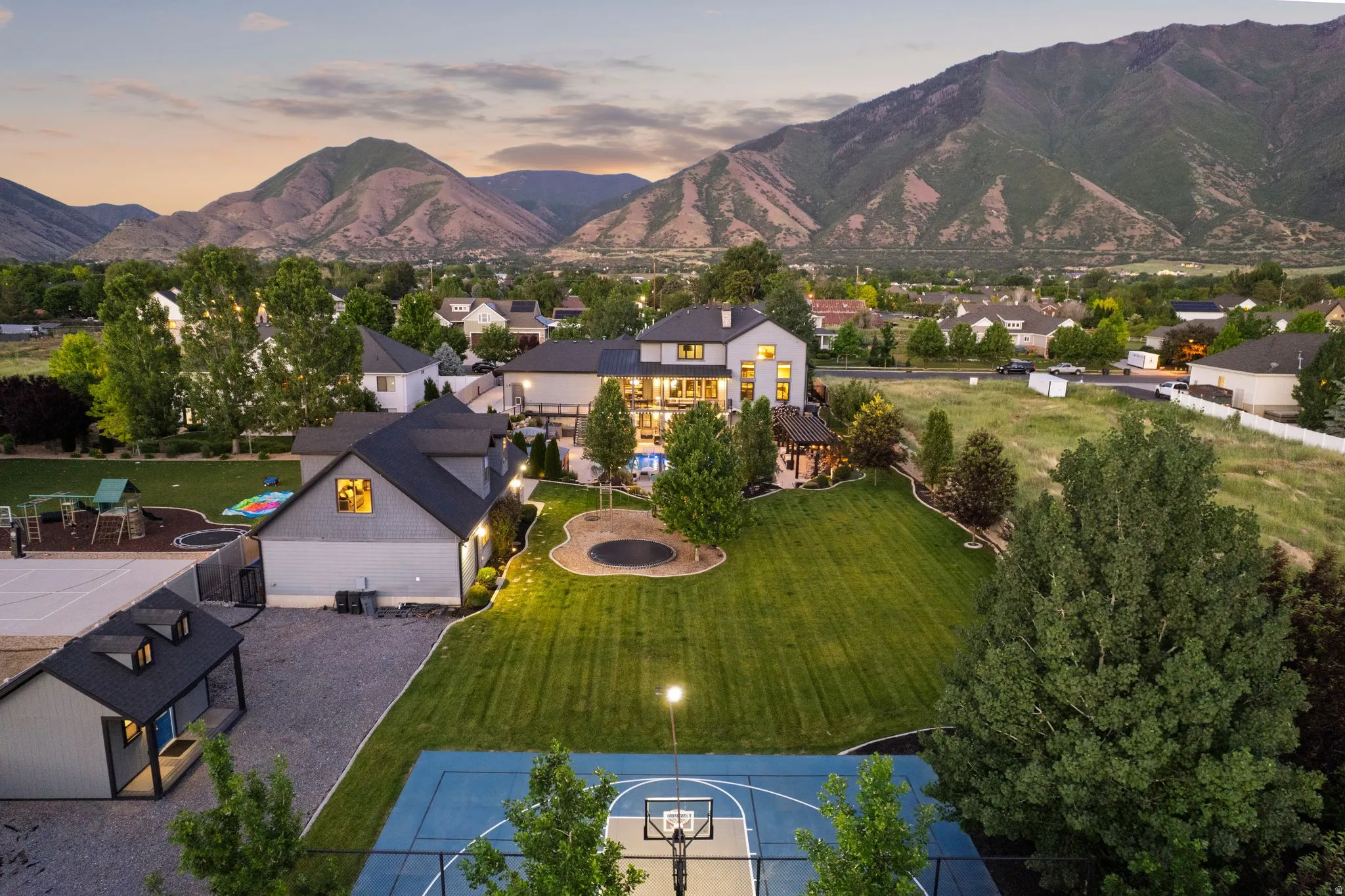 Spacious property featuring a large manicured lawn, full basketball court, and a separate structure with dormer windows