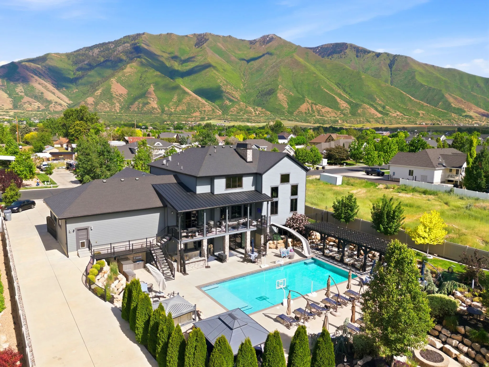 Contemporary multi-story residence featuring a large outdoor swimming pool with an attached slide, a spacious paved patio, and a covered pergola