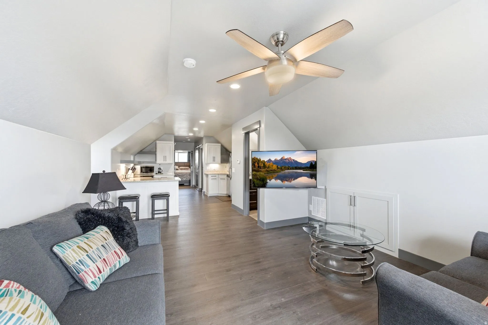 Open-concept living space featuring wood-finish flooring, a contemporary ceiling fan, recessed lighting, and built-in white cabinetry