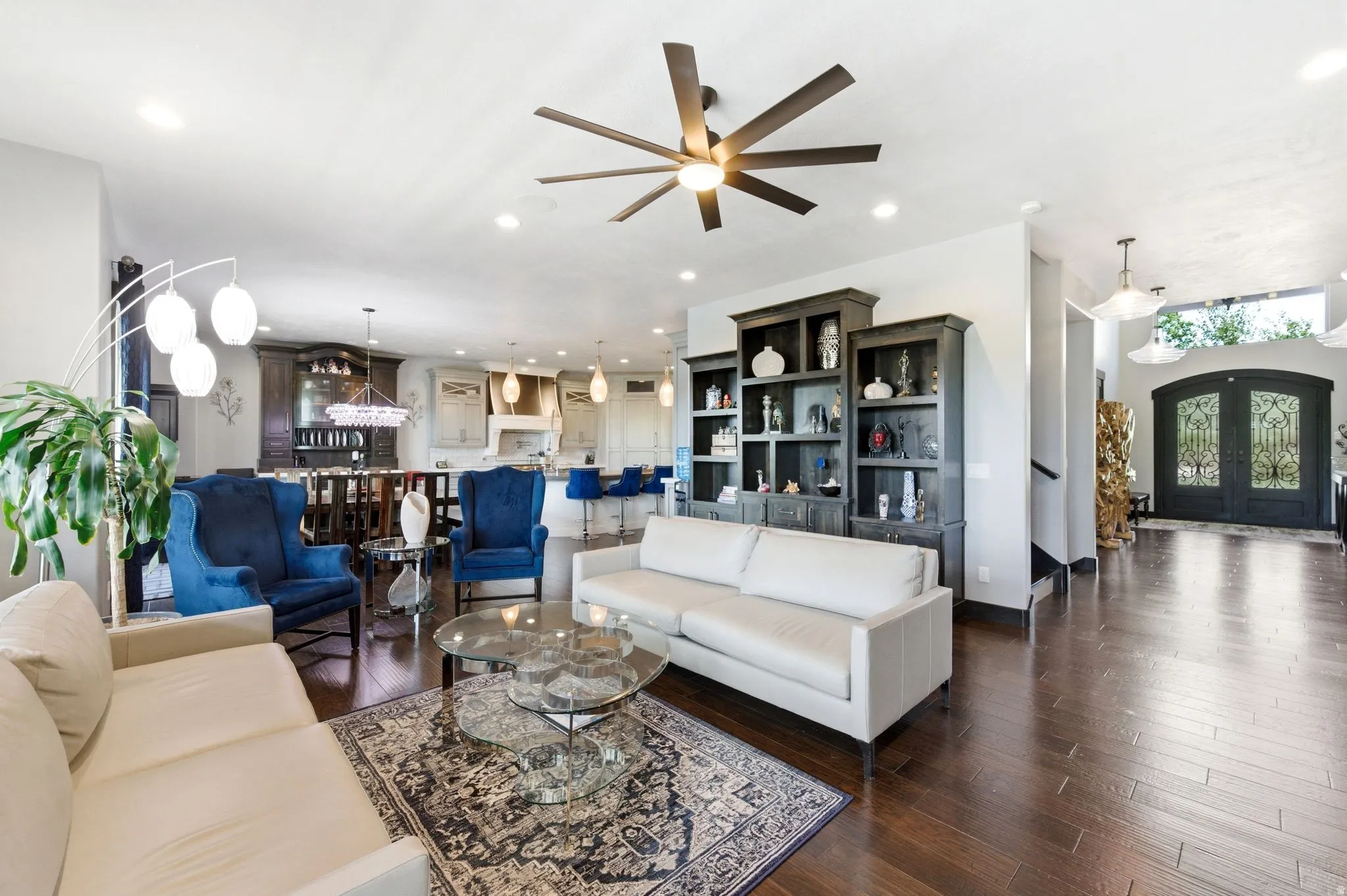 Open-concept living area featuring wood-finish flooring, a contemporary ceiling fan, and built-in shelving units