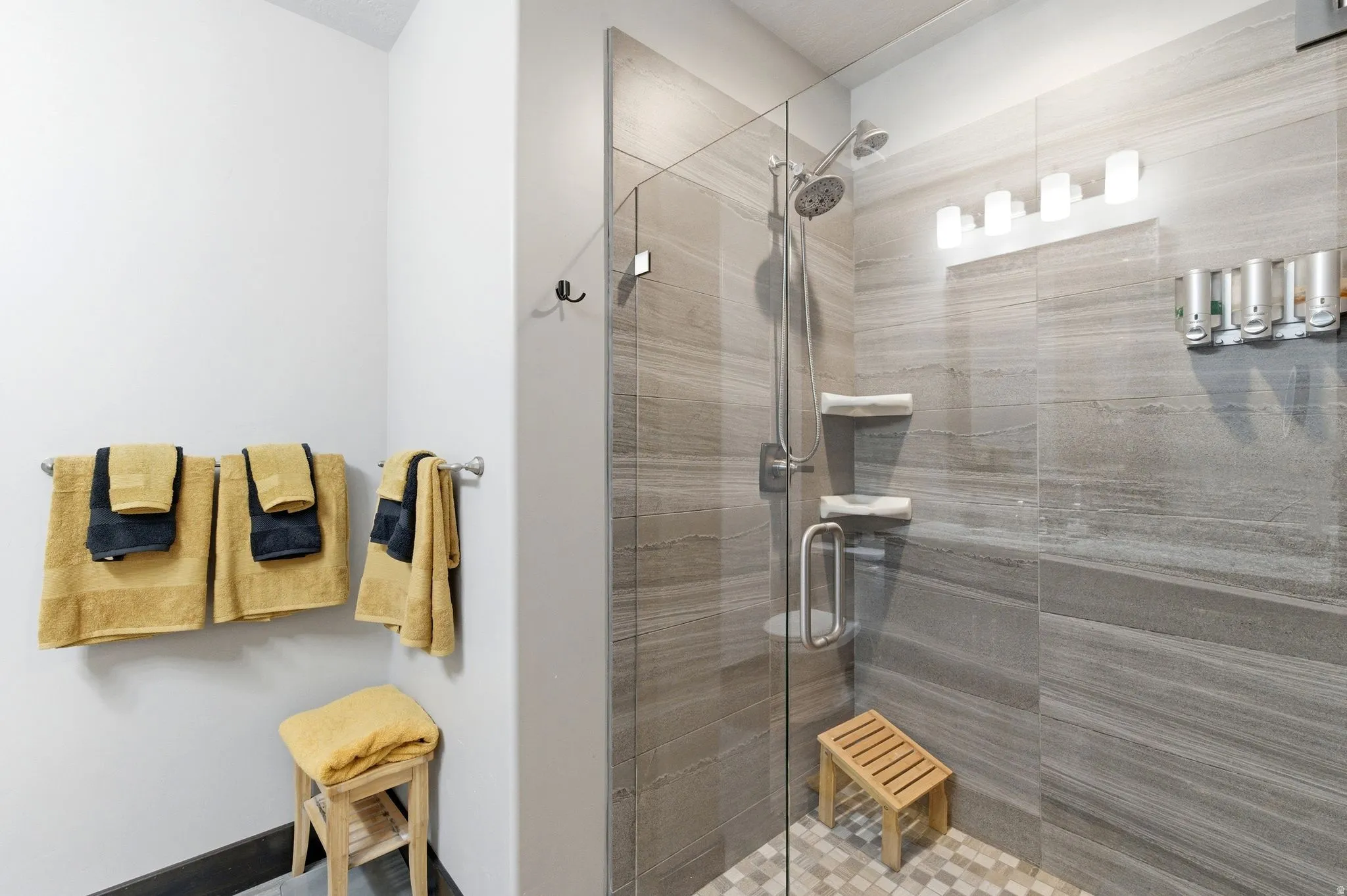 Walk-in shower featuring a glass enclosure, a handheld showerhead, and tiled walls with a banded pattern