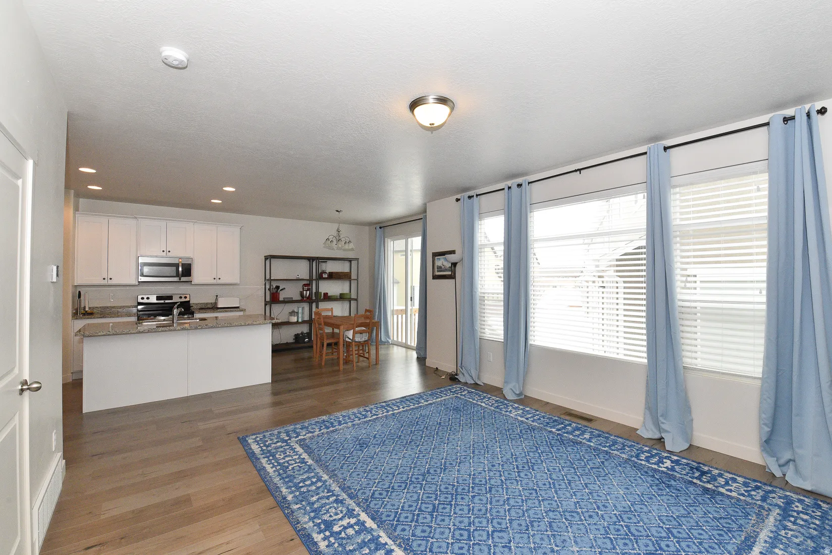 Open-concept living area with wood-finish flooring, recessed lighting, and large windows