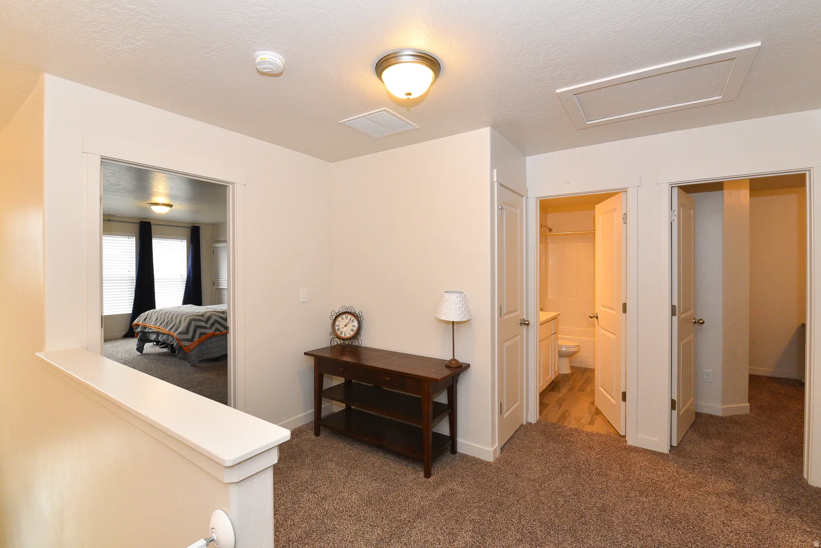 Neutral-toned hallway featuring plush carpeting, a built-in linen closet, and a half-wall overlooking another room