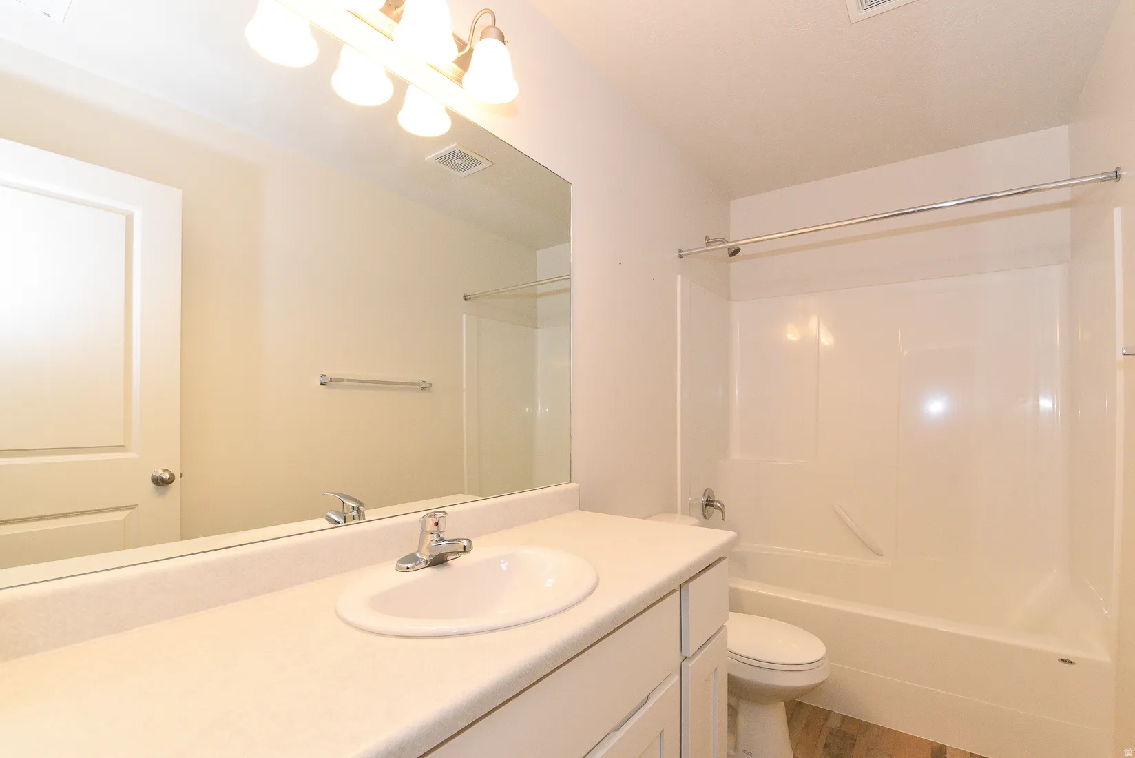 Bathroom featuring a white vanity with an integrated sink, polished chrome faucet, and overhead vanity lighting