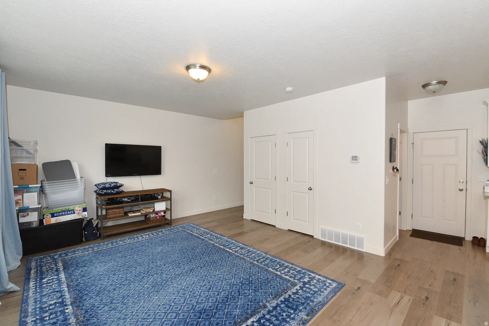 Open-concept living space featuring light wood-finish flooring, white walls, and flush-mount ceiling lighting