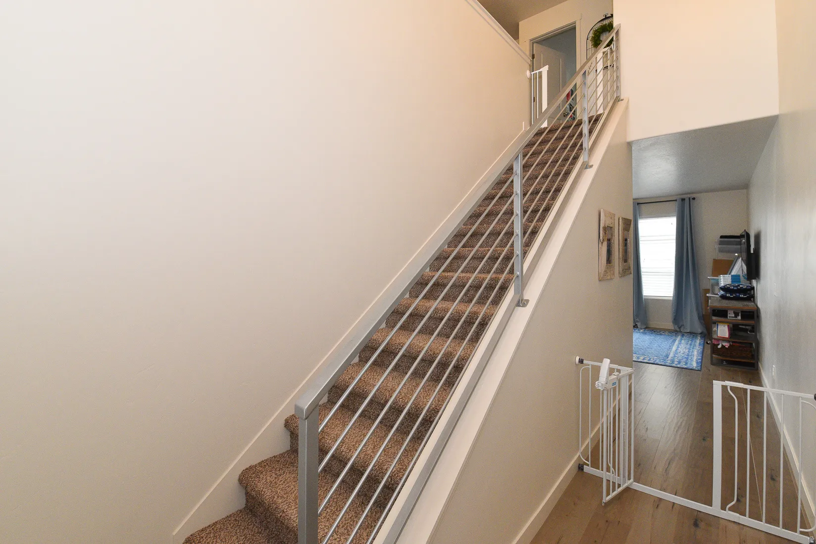 Staircase featuring contemporary metal railings and carpeted treads