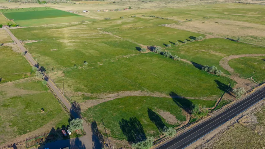 Expansive agricultural land featuring a paved road frontage, established green fields, and a dirt access road