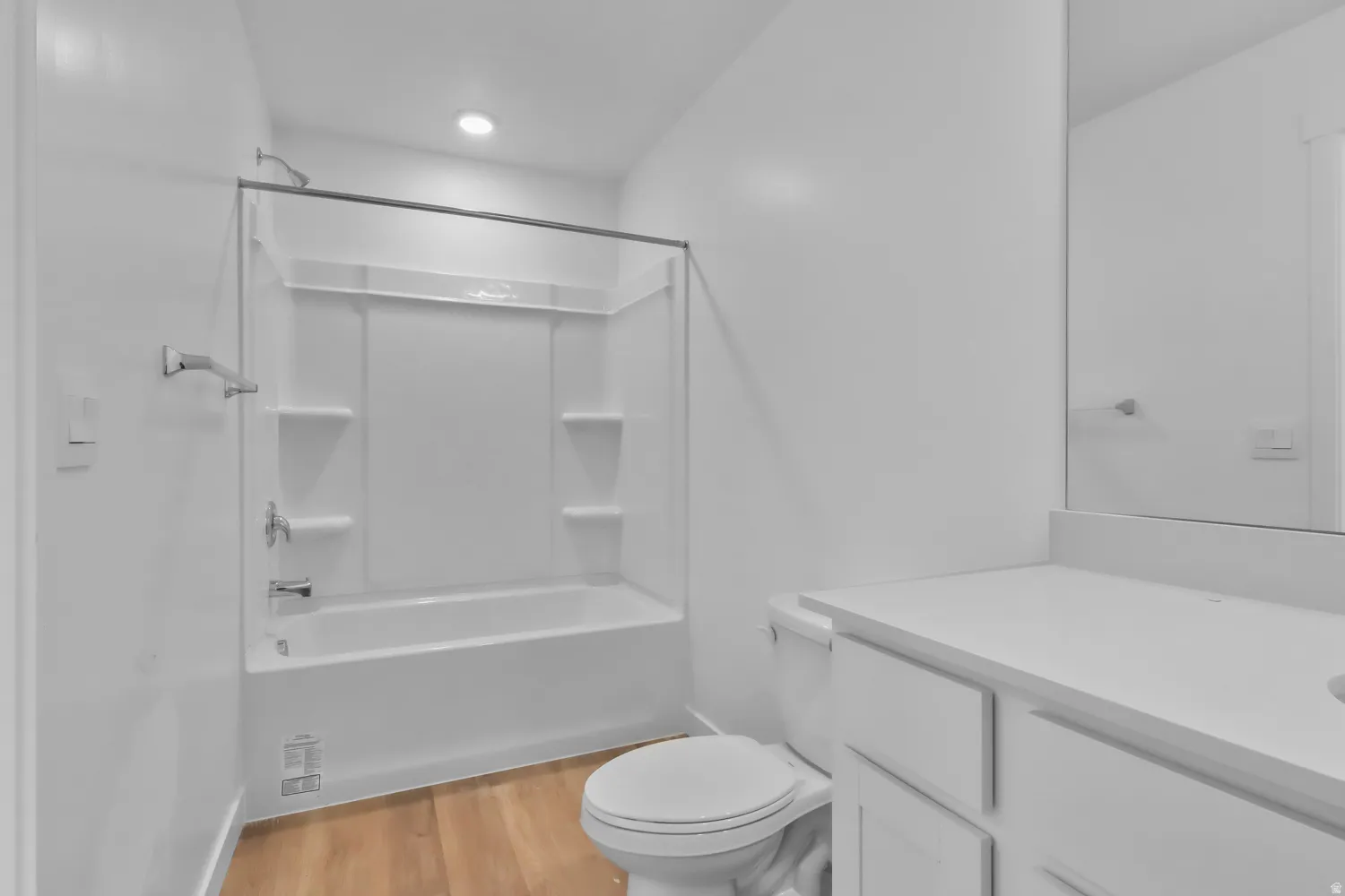 Bathroom featuring a white tub/shower combination, recessed lighting, chrome fixtures, wood-finish flooring, and a vanity with a white countertop